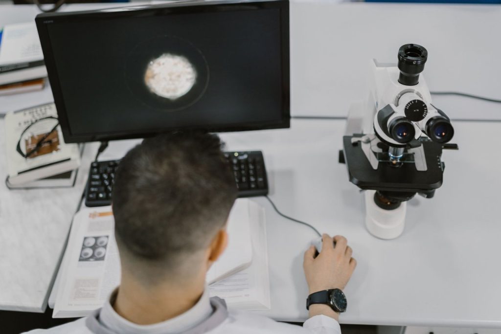 NASA prepara experimento de órgão-em-chip para a Artemis II Cientista observa uma amostra ao microscópio em um laboratório moderno.